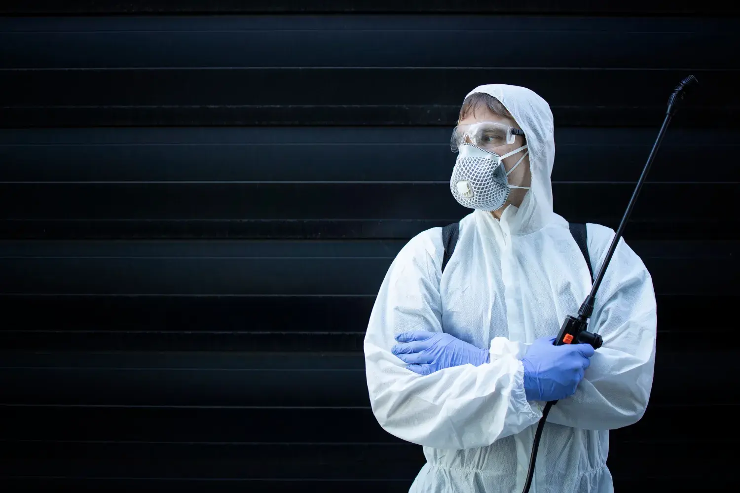 Pest control technician in protective gear with a sprayer
