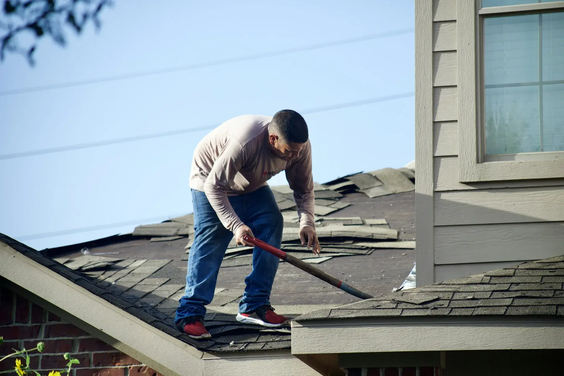 Roofer removing damaged shingles from a residential roof