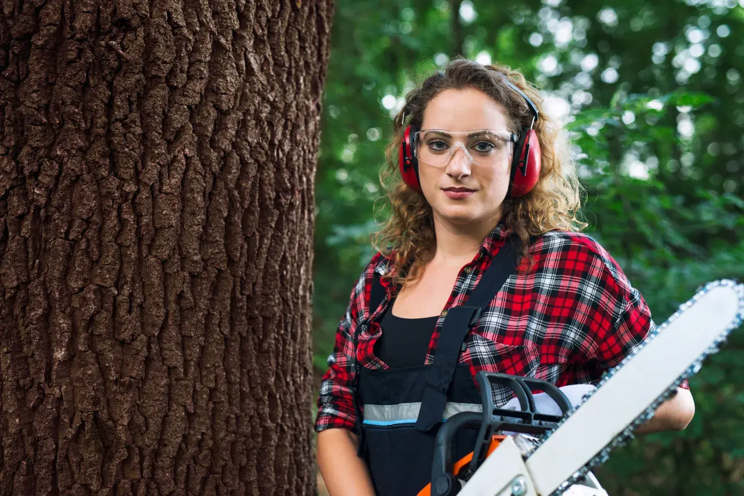 Tree service owner in safety gear holding a chainsaw