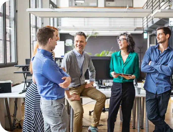 Team standing together talking in an open plan office Team standing together talking in an open plan office